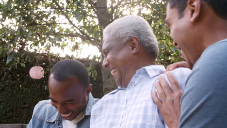 Black-dad-and-two-adult-sons-laughing-together-in-garden