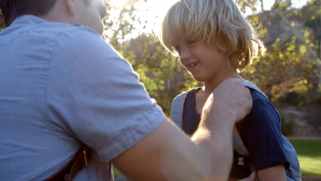 Father-Fastening-Son's-Backpack-As-They-Get-Ready-For-Hike