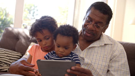Grandfather-And-Grandchildren-At-Home-Using-Digital-Tablet