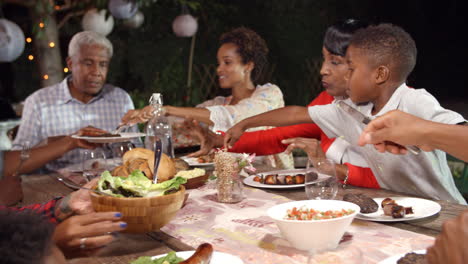 Schwarze-Familie-Mit-Mehreren-Generationen,-Die-Essen-Am-Tisch-Im-Freien-Serviert