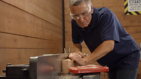 Male-Carpenter-Using-Plane-In-Woodworking-Woodshop