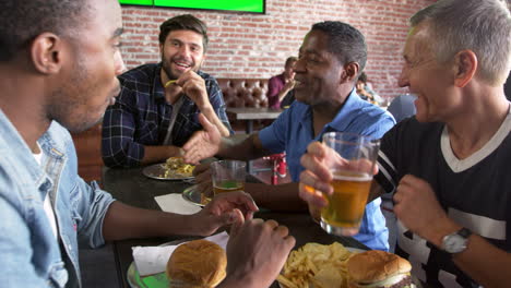 Group-Of-Male-Friends-Eating-Out-In-Sports-Bar-Shot-On-R3D