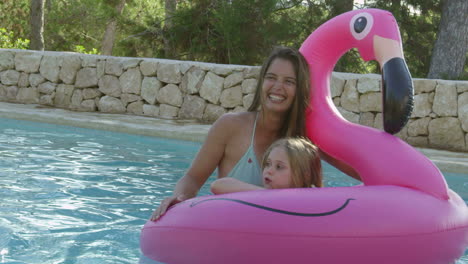Mother-And-Daughter-On-Inflatables-In-Outdoor-Swimming-Pool