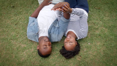 Young-black-couple-lying-on-grass-together,-shot-from-above