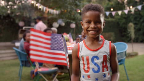 Young-black-boy-waving-US-flag-at-4th-July-family-barbecue