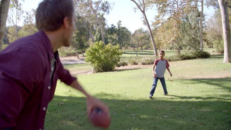 Seven-year-old-boy-throwing-football-with-his-dad-in-park