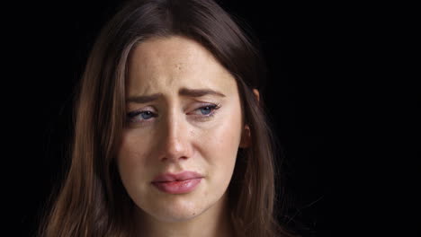 Studio-Shot-Of-Unhappy-Young-Woman-Crying-Into-Camera