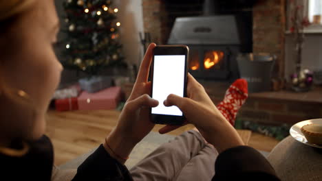 Woman-On-Line-With-Mobile-Phone-In-Room-Ready-For-Christmas