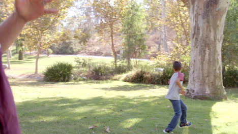 Dad-and-son-passing-American-football-to-each-other-in-park