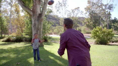 Boy-and-his-dad-playing-with-American-football-in-a-park