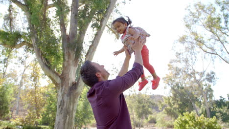 Father-throwing-his-young-daughter-in-the-air-in-a-park