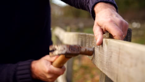 Close-Up-Of-Man-Hammering-Nail-Into-Fence-In-Slow-Motion