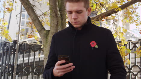 Man-Wearing-Remembrance-Day-Poppy-Using-Mobile-Phone