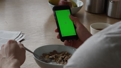 Man-Using-Smartphone-With-Green-Screen-And-Eating-Breakfast