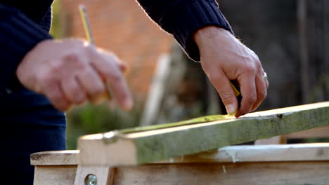 Mature-Man-Measuring-And-Sawing-Wood-In-Slow-Motion