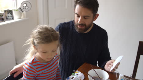 Father-And-Daughter-Making-Halloween-Masks-At-Home-Together