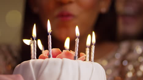 Frau-Bläst-Kerzen-Auf-Geburtstagstorte-Aus