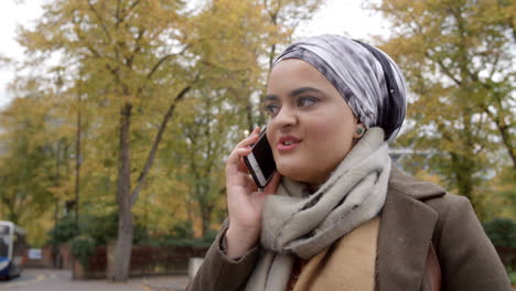 Mujer-Musulmana-Británica-Usando-Teléfono-Móvil-En-El-Parque