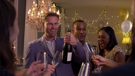 Freunde-öffnen-Champagner,-Während-Sie-Gemeinsam-Auf-Einer-Party-Feiern