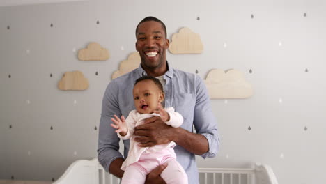 Father-Holding-Baby-Daughter-In-Nursery-Shot-In-Slow-Motion