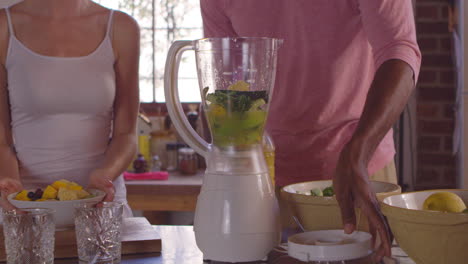 Mixed-race-couple-making-smoothies-using-blender,-close-up,-shot-on-R3D