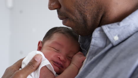 Father-Cuddling-Sleeping-Newborn-Baby-Son-In-Nursery