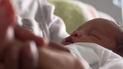 Close-Up-Of-Parents-Cuddling-Newborn-Baby-Son-In-Nursery
