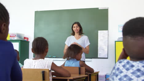 Profesor-Haciendo-Una-Pregunta-A-Niños-De-Escuela-Primaria-En-Clase.