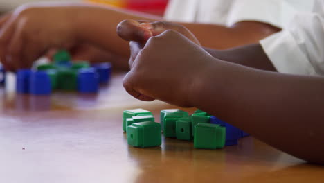Elementary-school-kids'-hands-playing-with-blocks,-close-up
