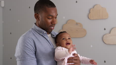 Portrait-Of-Father-Holding-Baby-Daughter-In-Nursery