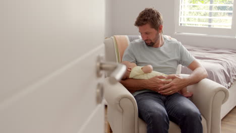 Father-Sitting-In-Nursery-Chair-Holds-Sleeping-Baby-Son