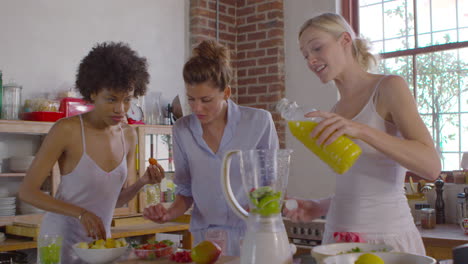 Three-female-friends-making-smoothies-together-in-kitchen,-shot-on-R3D