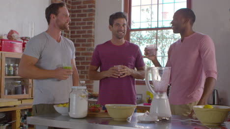 Three-male-friends-with-homemade-smoothies-talking-in-kitchen,-shot-on-R3D