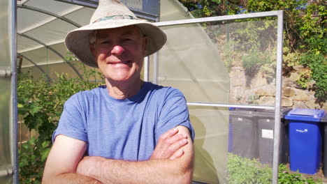 Portrait-Of-Senior-Male-Gardener-Outside-Allotment-Greenhouse