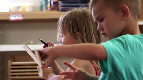 Alumnos-Montessori-Escribiendo-Sobre-Formas-De-Madera-En-El-Aula.