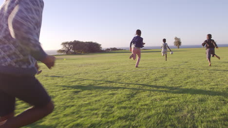 Elementary-school-kids-chasing-football-in-a-field