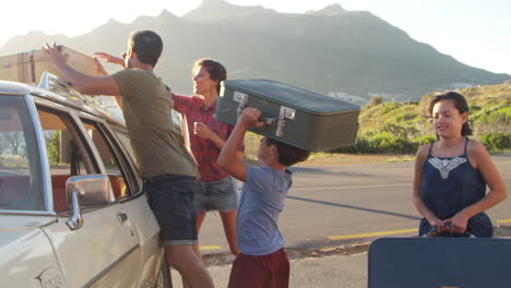 Family-Loading-Luggage-Onto-Car-Roof-Rack-Ready-For-Road-Trip