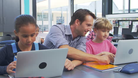 Lehrer-Hilft-Jungen-Schülern-Bei-Der-Verwendung-Von-Laptops-Im-Unterricht