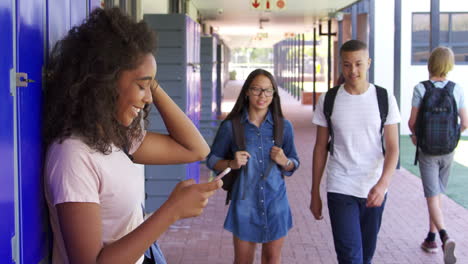 Three-teenage-friends-talk-in-school-corridor,-slow-motion