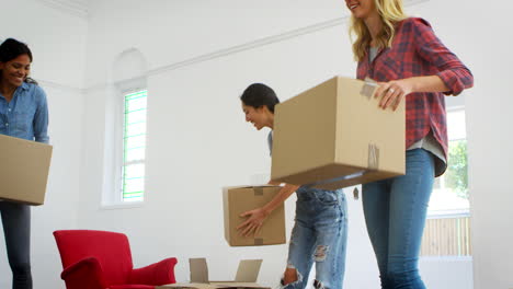Three-Female-Friends-Carrying-Boxes-Into-New-Home-On-Moving-Day