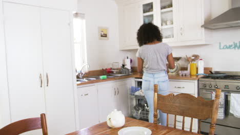Teenage-Girl-Clearing-Breakfast-Table-And-Loading-Dishwasher