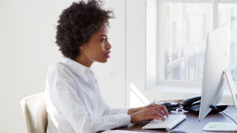 Young-black-woman-working-at-computer-in-an-office,-close-up