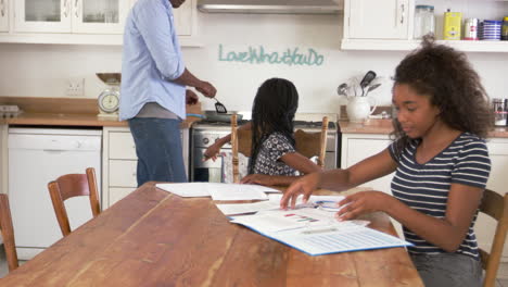 Vater-Hilft-Zwei-Töchtern,-Die-Am-Tisch-Sitzen-Und-Hausaufgaben-Machen