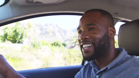 Young-smiling-black-man-driving-car-on-a-road-trip