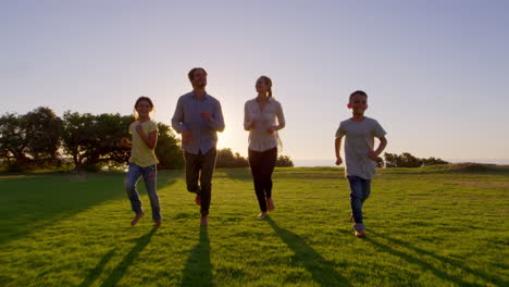 Young-white-family-running-towards-moving-camera-in-a-park