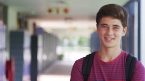 White-teenage-boy-walks-into-focus-in-high-school-corridor