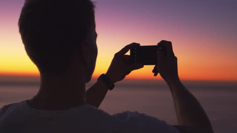 Mann,-Der-Panoramafoto-Mit-Telefon-An-Einem-Strand-Bei-Sonnenuntergang-Macht
