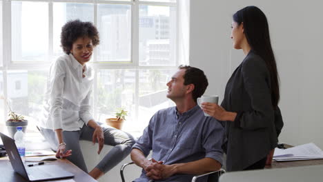 Young-man-and-two-female-colleagues-talking-in-an-office