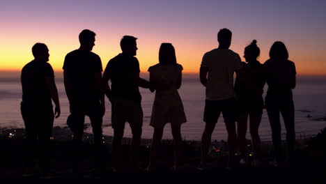 Gruppe-Junger-Erwachsener,-Die-Sich-Bei-Sonnenuntergang-Am-Strand-Unterhalten