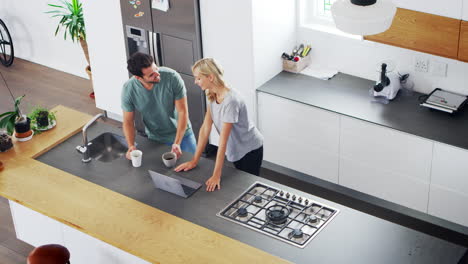 Overhead-View-Of-Couple-Looking-At-Laptop-In-Modern-Kitchen